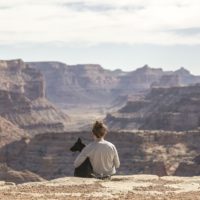 girl holding her black dog in clear blue sky while looking at the mountains