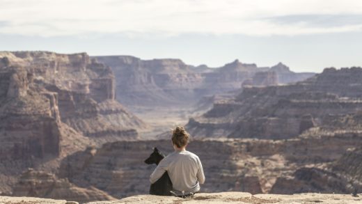 girl holding her black dog in clear blue sky while looking at the mountains